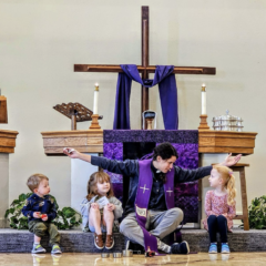 Pastor Cecie sits at the front of the church, arms outstretched as she speaks to small children.